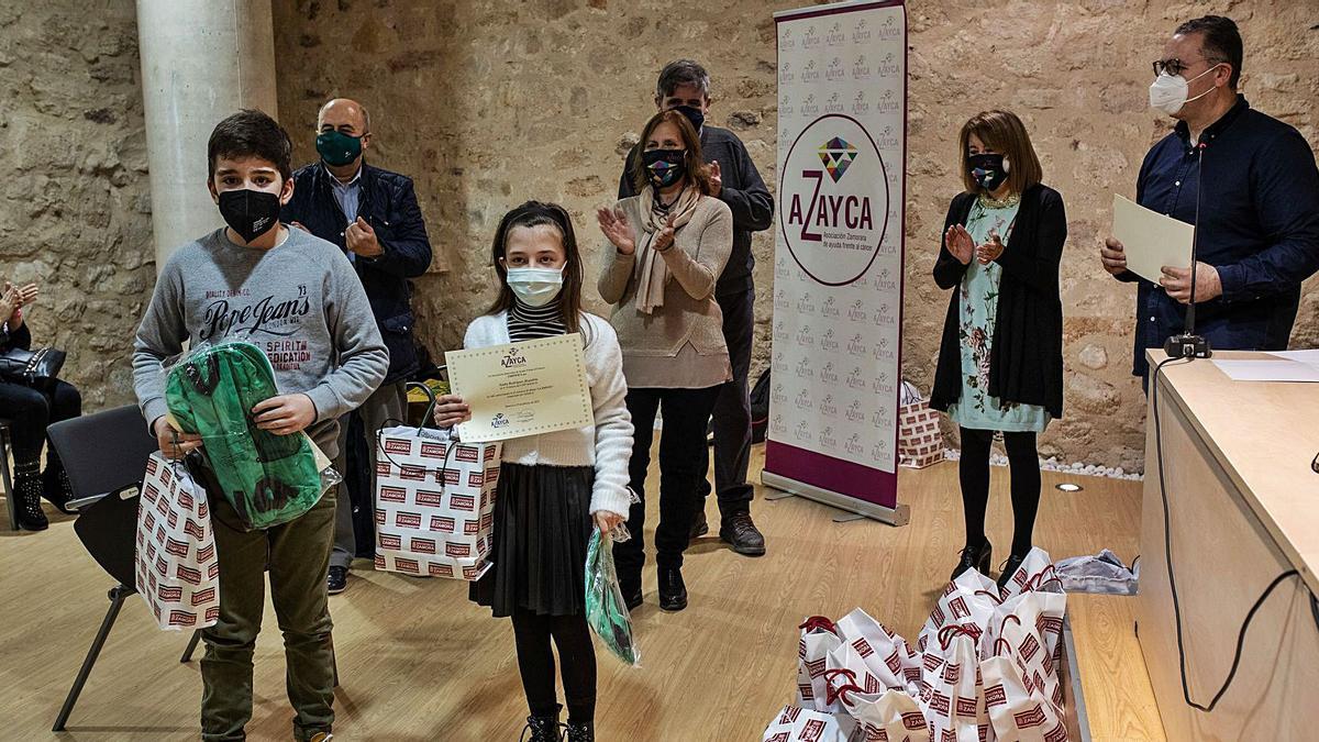 Dos niños recogen los premios por su participación en el concurso de dibujo de Azayca.