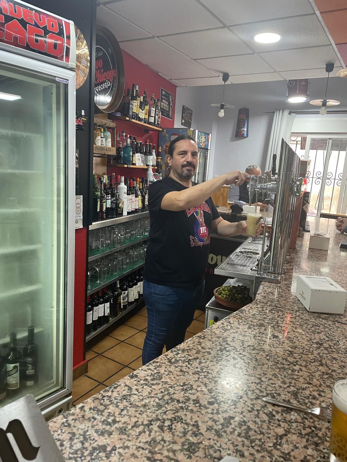 El dueño de El Chicago, Jose, detrás de la barra sirviendo una cerveza muy fría.