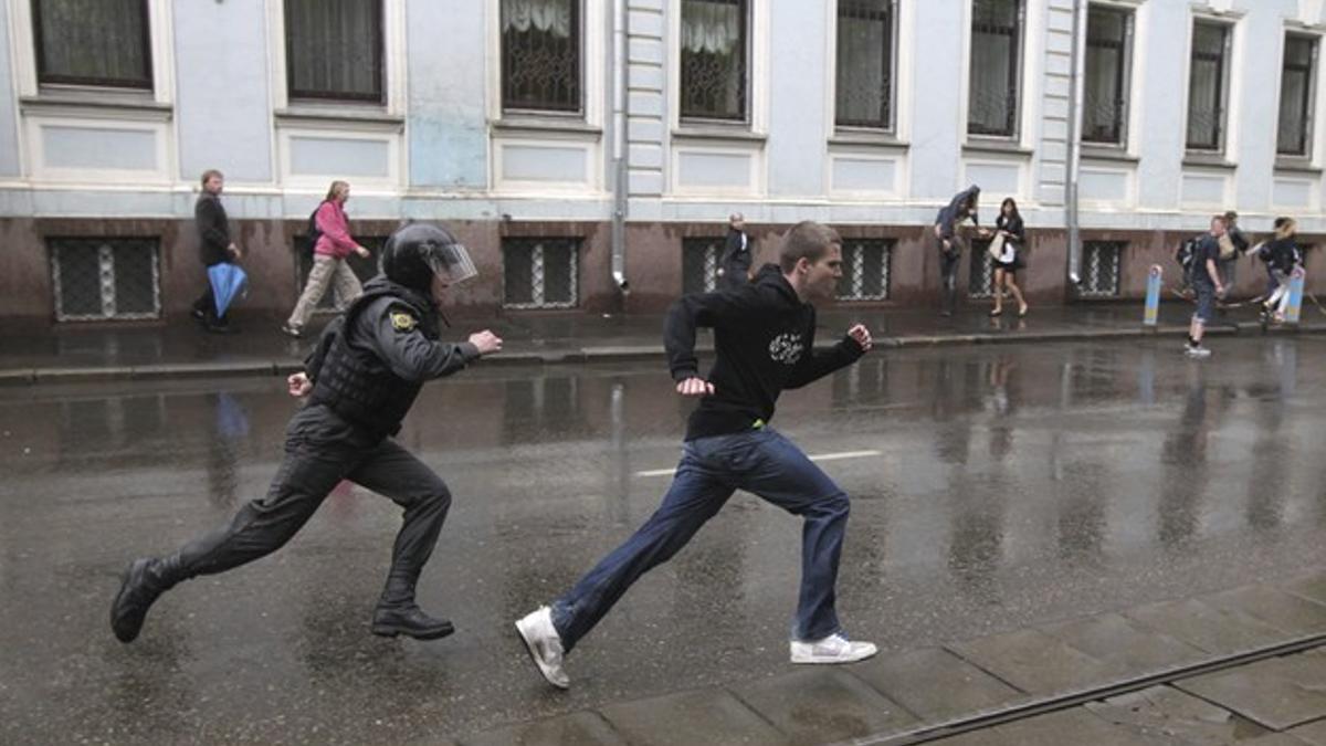 Un policía antidisturbios persigue a un joven que participaba en una manifestación contra el nombramiento de Vladimir Putin en Moscú