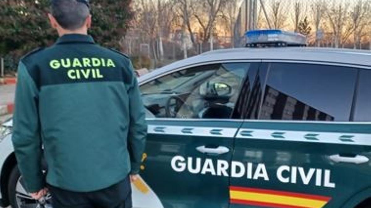 Imagen de archivo de un coche patrulla de la Guardia Civil y un agente.
