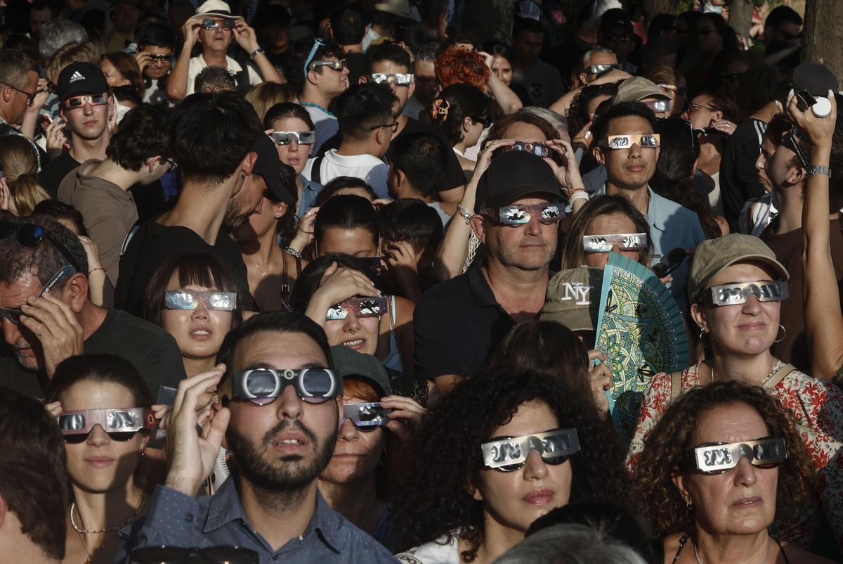 Una multitud de personas espera con gafas protectoras el comienzo del eclipse de Sol en Madrid este miércoles