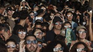Una multitud de personas espera con gafas protectoras el comienzo del eclipse de Sol en Madrid este miércoles