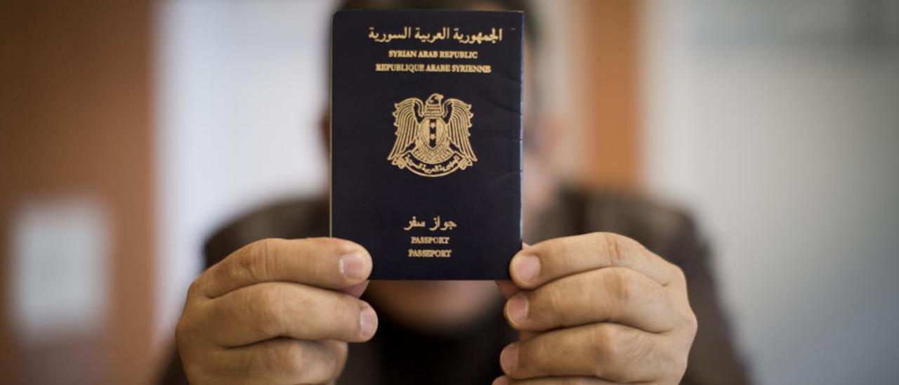 Tamer Karim oculta su rostro detrás de su pasaporte.