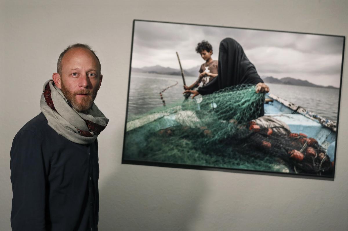 El fotógrafo argentino Pablo Tosco, premiado en el World Press Photo 2021 en la categoría de ’Asuntos contemporáneos’, posa junto a su fotografía, expuesta en el CCCB.