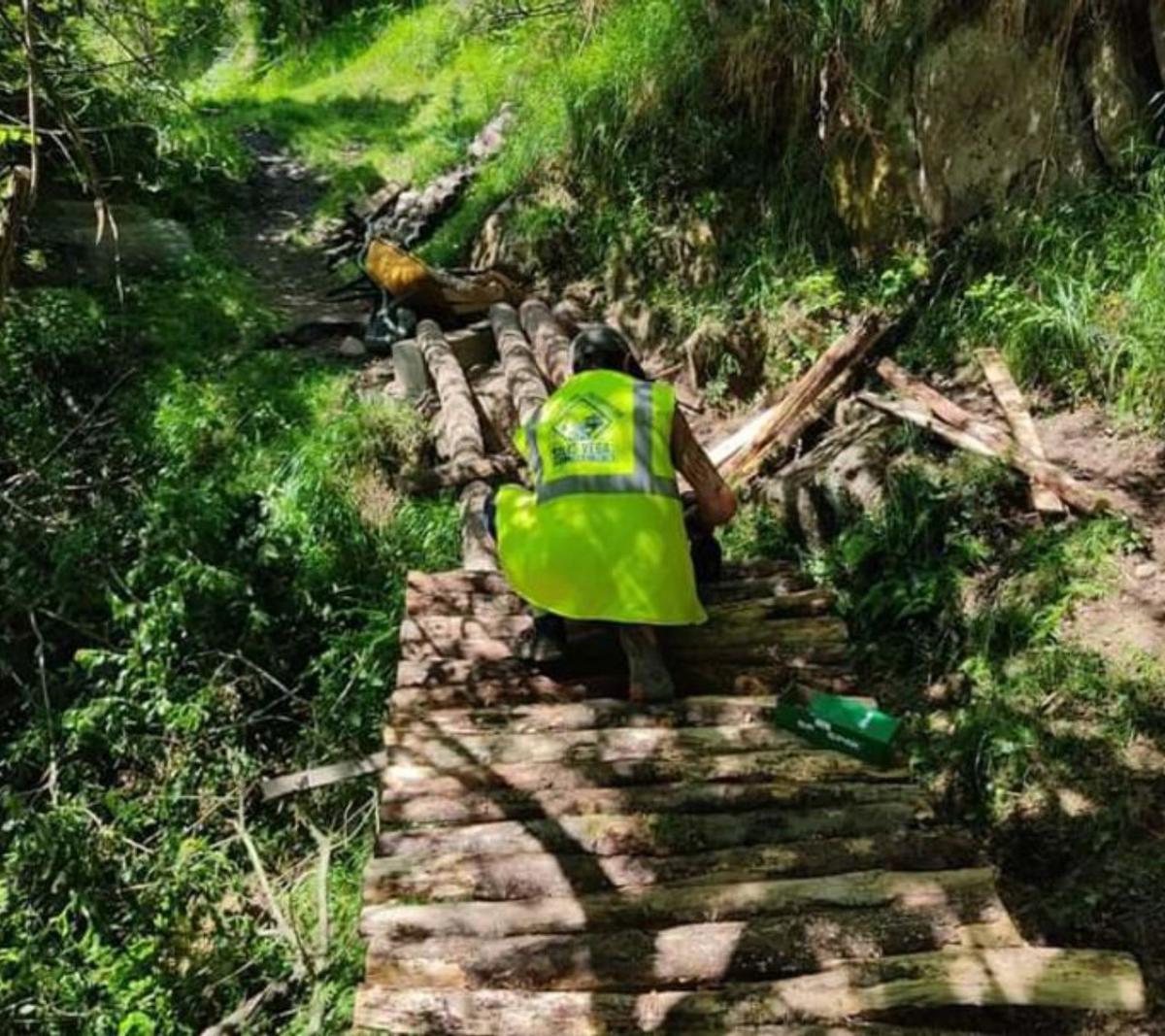Un trabajador habilita un paso de troncos de madera en un nuevo tramo denominado Los Mineros.