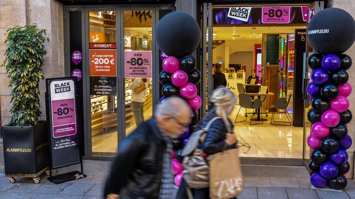 Dos transeúntes pasan por delante de una tienda que anuncia sus descuentos durante el Black Friday del año pasado