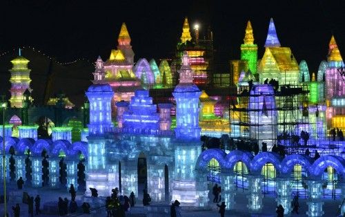 Workers and scaffoldings are seen next to newly-built ice sculptures illuminated by coloured lights ahead of the 30th Harbin Ice and Snow Festival, in Harbin