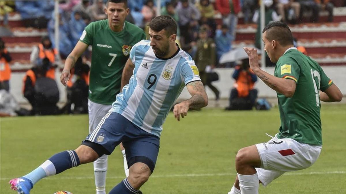Pratto intenta superar a dos jugadores de Bolivia