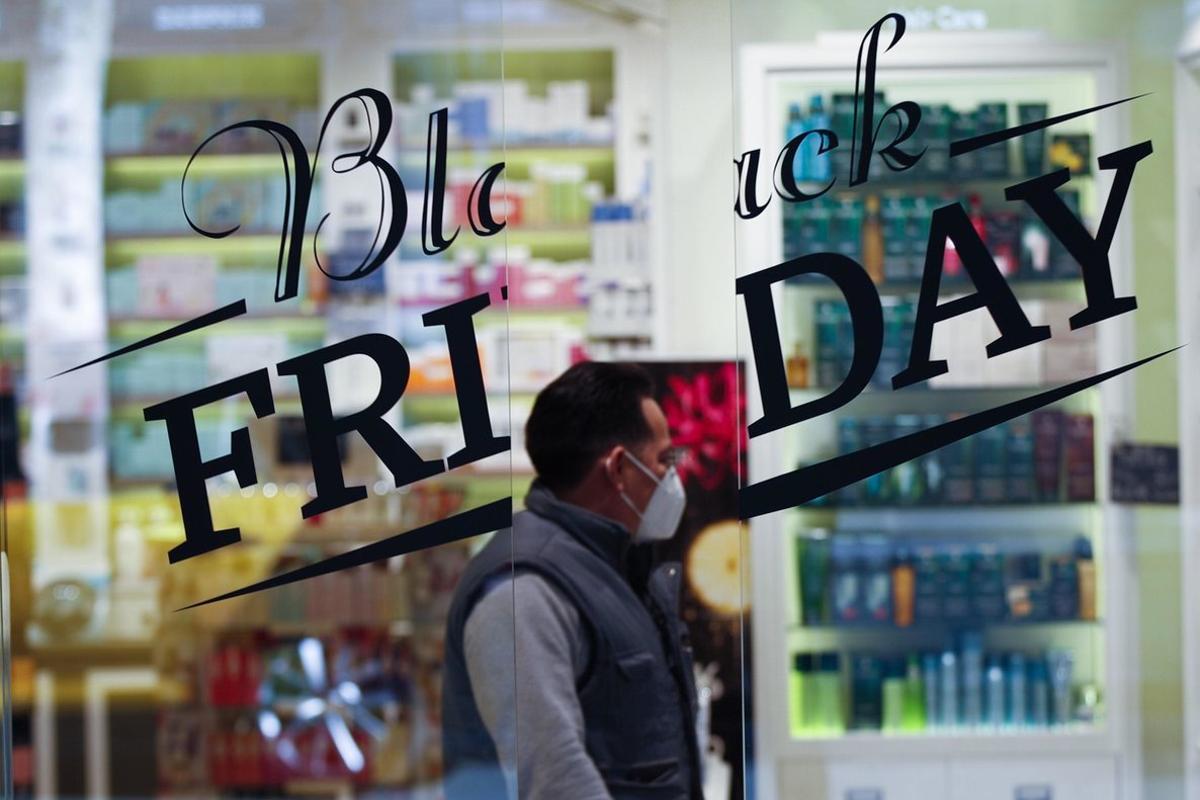 GRAFCAT4982. BARCELONA, 24/11/2020.- Una persona pasa ante un comercio que anuncia descuentos por el Black Friday, la fiesta del comercio importada de Estados Unidos que da el pistoletazo de salida a la campaña de Navidad, y que los comerciantes catalanes afrontan con la esperanza de empezar a dar salida al stock acumulado durante estos meses y la incertidumbre de cómo se comportarán este año los consumidores. EFE/Alejandro García.