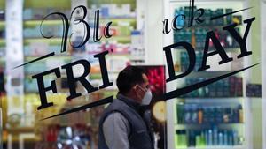 GRAFCAT4982. BARCELONA, 24/11/2020.- Una persona pasa ante un comercio que anuncia descuentos por el Black Friday, la fiesta del comercio importada de Estados Unidos que da el pistoletazo de salida a la campaña de Navidad, y que los comerciantes catalanes afrontan con la esperanza de empezar a dar salida al stock acumulado durante estos meses y la incertidumbre de cómo se comportarán este año los consumidores. EFE/Alejandro García.