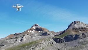 Un dron vuela con un paisaje montañoso de fondo.