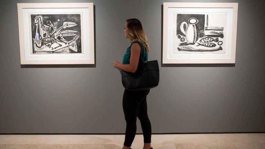 Una persona observa la obra «El bogavante» (i) junto a «La mesa con pescados», ambas de Pablo Picasso.