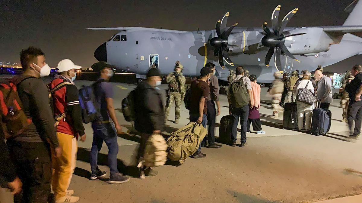 Los ciudadanos franceses y sus colegas afganos esperan para acceder a un avión de transporte militar francés en el aeropuerto de Kabul.