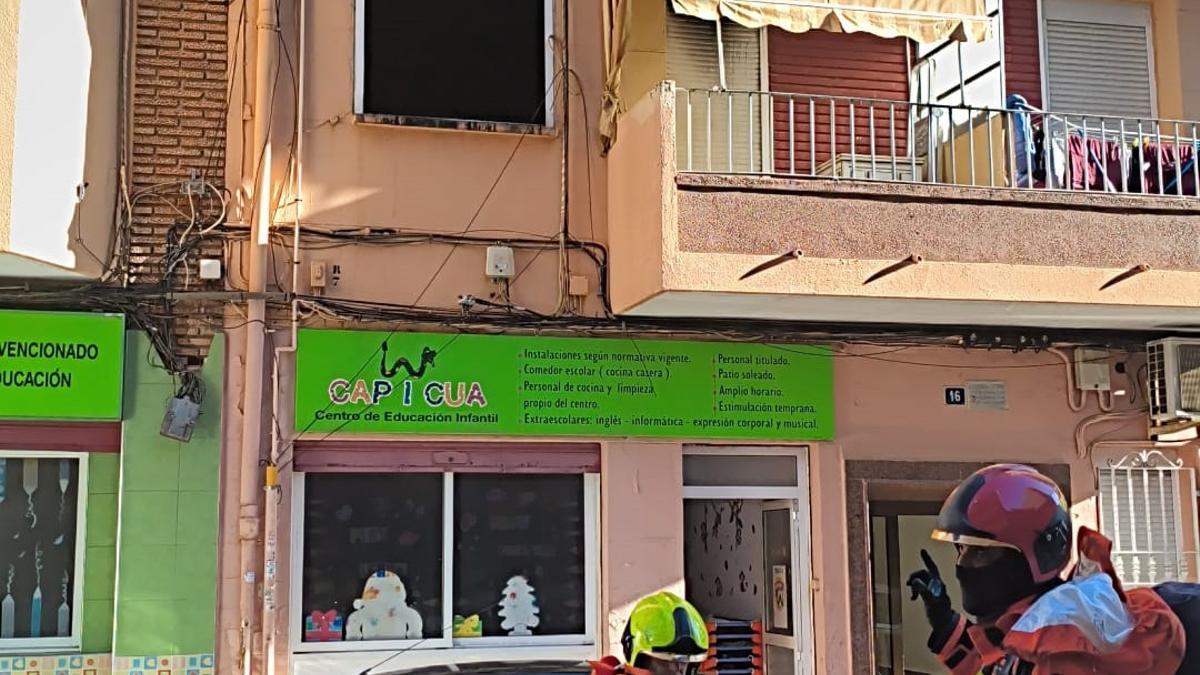 Bomberos frente al piso calcinado y el centro de educación infantil evacuado en Torrent.