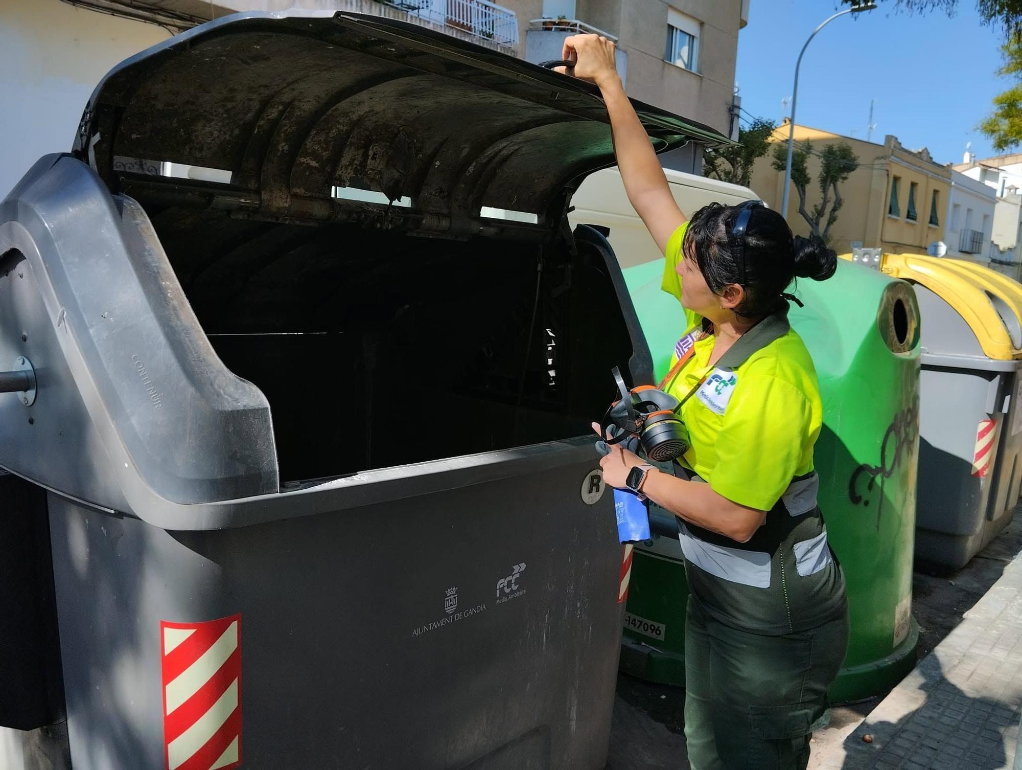 Una operaria limpia un contenedor de Gandia.