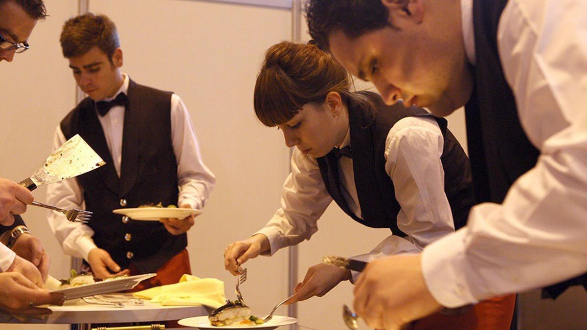 Un grupo de jóvenes camareros preparan los platos en un eve