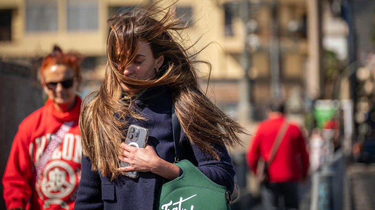 Una mujer sufre las acometidas de las fuertes rachas de viento en la capital tinerfeña.
