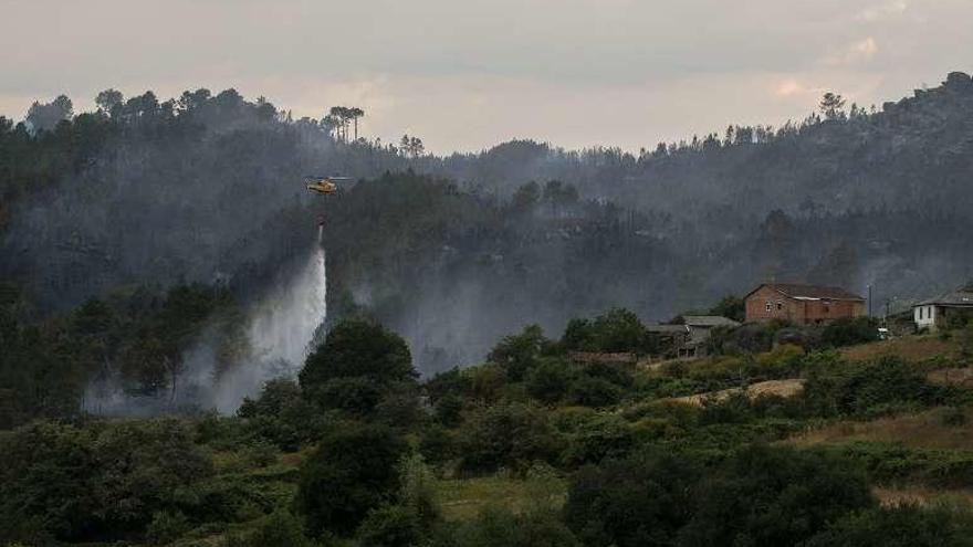 Un helicóptero, descargando agua cerca de una aldea. // Brais Lorenzo