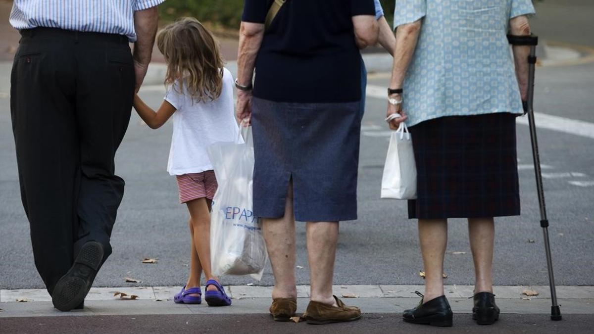 Tres generaciones de ciudadanos a la espera de cruzar una acera.