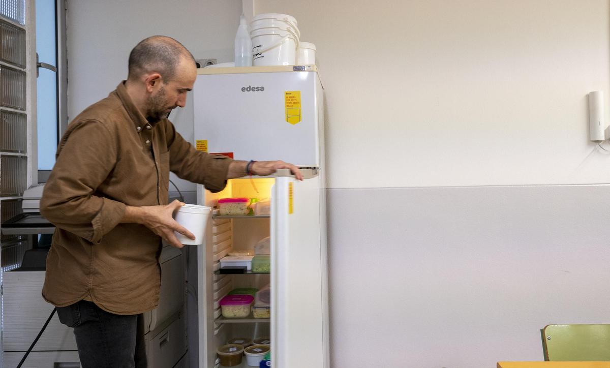 Pablo Peralta, presidente de la afa, coge de la 'Nevera Verda' de la escuela Diputació uno de los 'tuppers' recuperados.