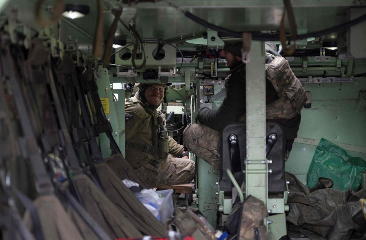 Militares ucranianos hablan en un transporte blindado de personal (APC) después de llevar a un militar ucraniano herido desde una posición de primera línea a un punto de evacuación cerca de la línea de frente de Bakhmut.