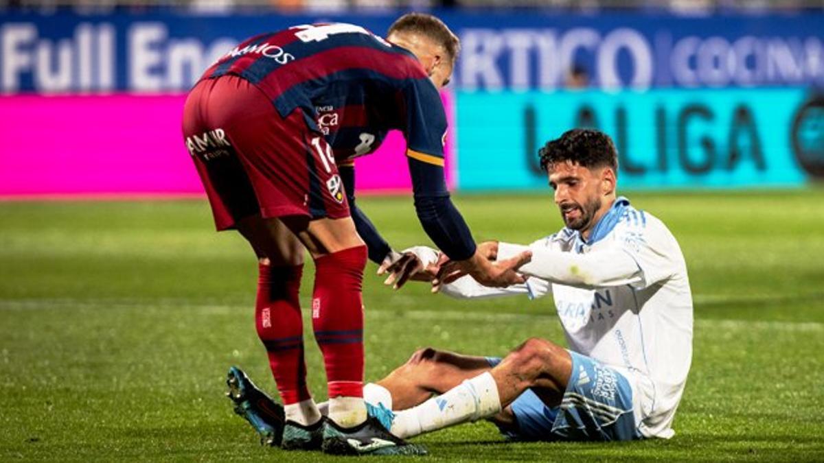 Jorge Pulido ayuda a Kenan Kodro a levantarse en el partido entre el Real Zaragoza y el Huesca.