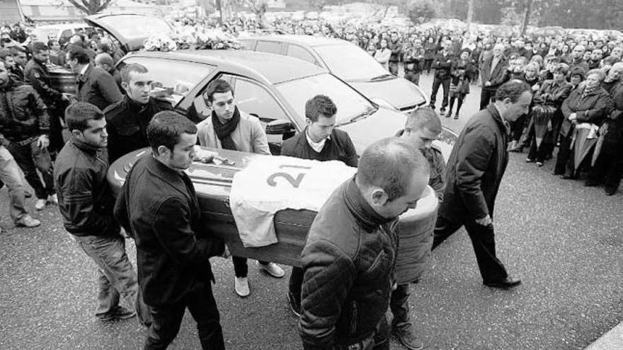 Amigos de los fallecidos portan los féretros. El de Roberto, con una camiseta del equipo donde jugó. / j.d.a.