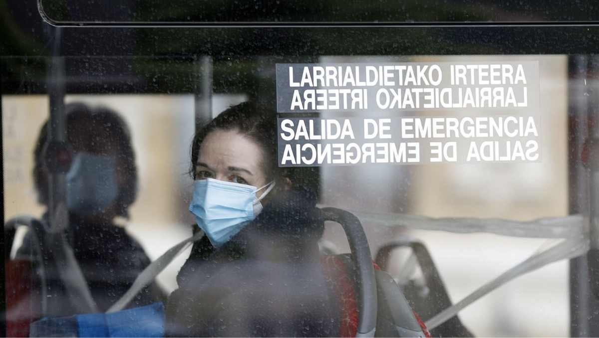 Una persona con mascarilla en un autobús.