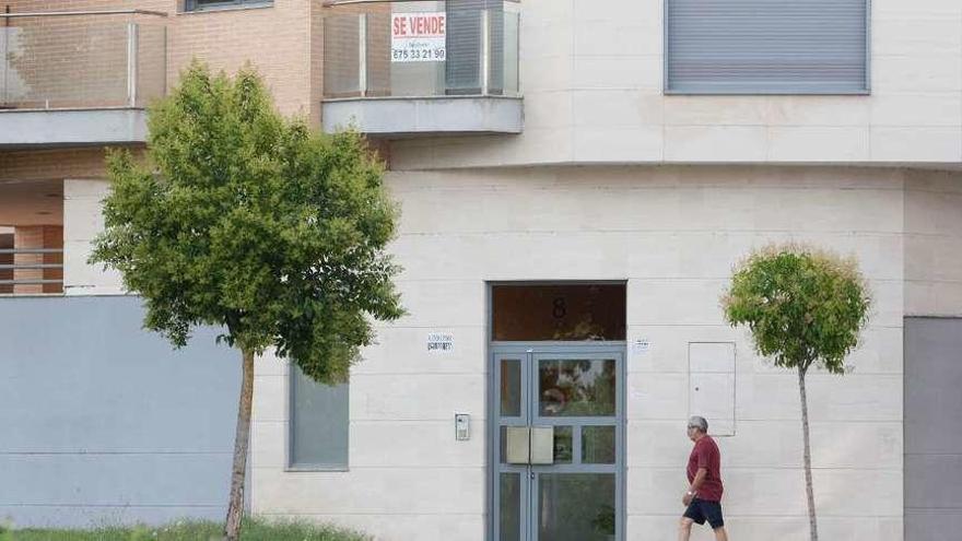 Un hombre camina junto a un edificio nuevo en el que se vende una vivienda.