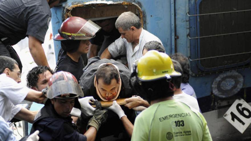 Policías y bomberos rescatan a un pasajero atrapado en uno de los vagones del tren siniestrado.