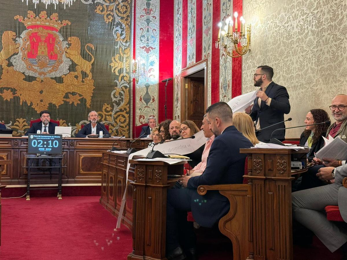 Rafa Mas, portavoz de Compromís, muestra un listado con ciudades que aplican la tasa turística.