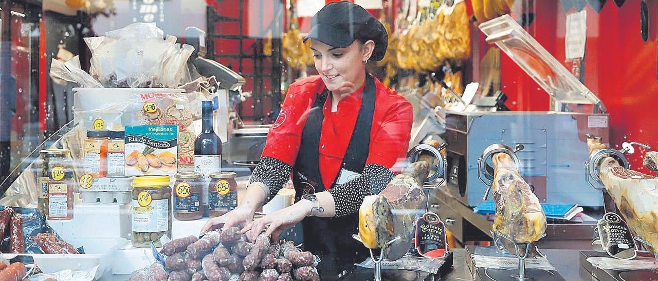 Una dependienta prepara los productos en el escaparate de un comercio.