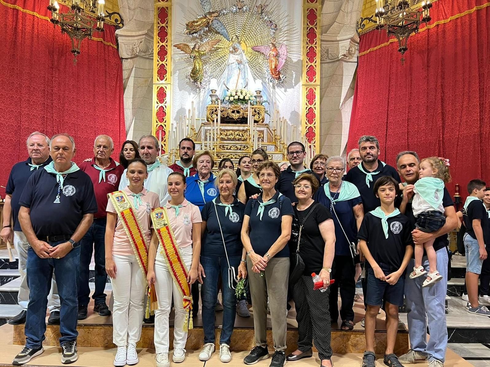 Miembros de la Cofradía de la Virgen con el cura y las regidoras de fiestas en la iglesia de Santiago con La Morenica en el altar mayor.