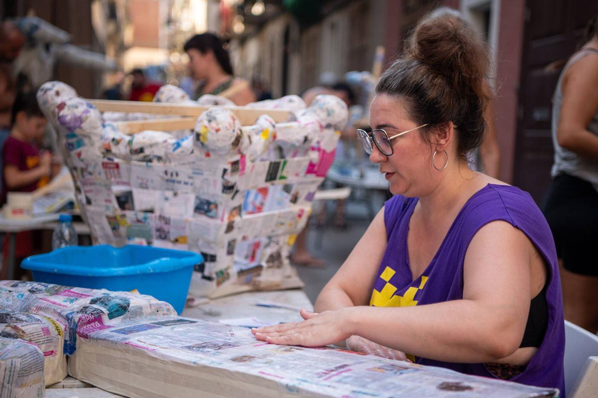 Una vecina de la calle Congrés trabajando en la creación de ‘guarnits’ para las fiestas mayores de Gràcia. Este año, 5 calles del barrio se han unido bajo la temática de ‘El Señor de los Anillos’. Barcelona, 4 de agosto de 2026. Foto: Belén González / EP