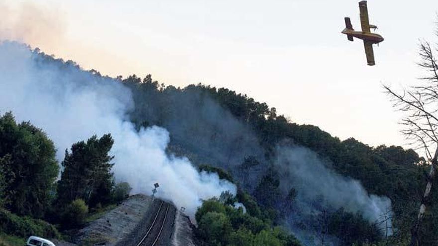 Un hidroavión sobrevuela un foco del incendio que irrumpe en la vía del tren, entre Maside y Santa Cruz de Arrabaldo. // Brais Lorenzo