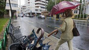 Una mujer camina bajo la lluvia con su paraguas