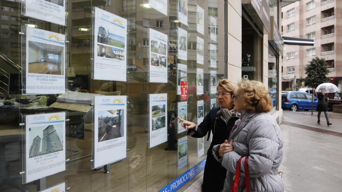 Persones mirant anuncis de vendes de pisos a una immobiliària.