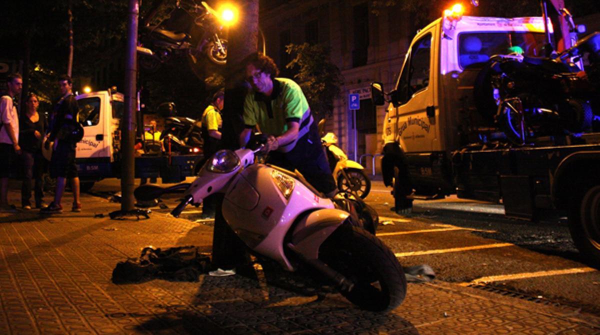 Els propietaris de les motocicletes observen com la grua s’emporta els seus vehicles.