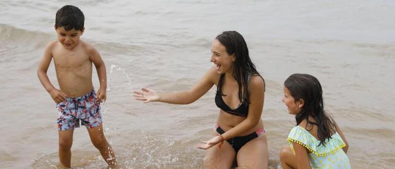 Enol y Noa Vallina juegan con Karolina García, en el centro, en la playa gijonesa de San Lorenzo.