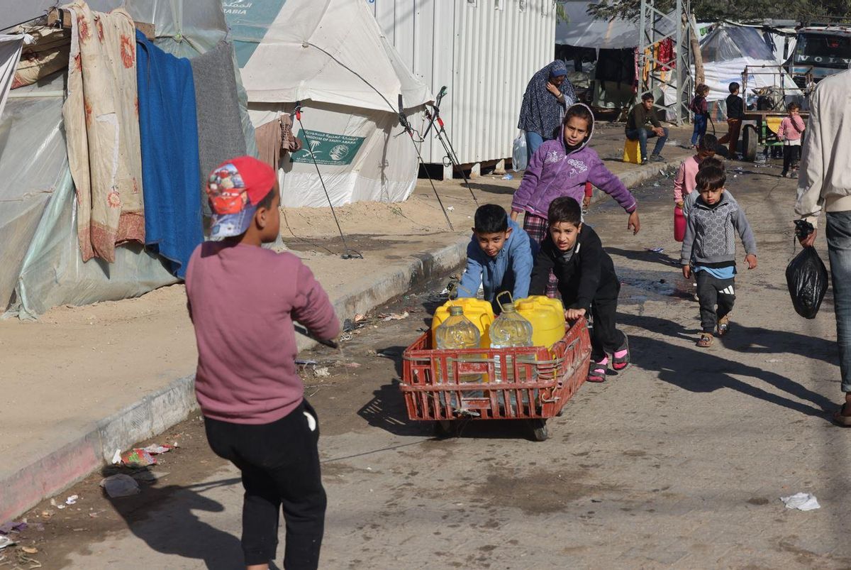 Niños palestinos desplazados transportan agua potable en el barrio de Al-Shaboura, Rafah.