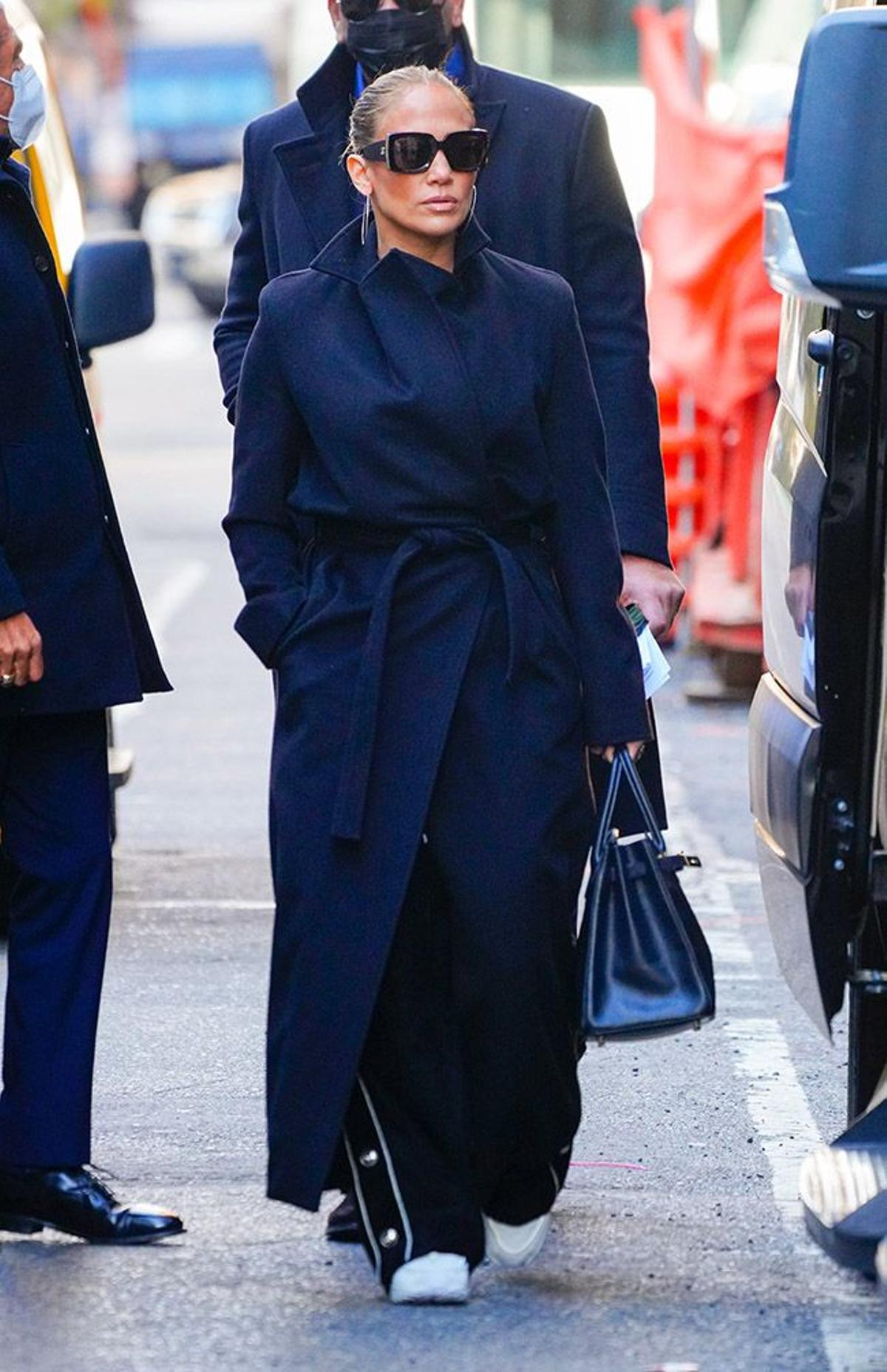 Jennifer Lopez con abrigo masculino, gafas y el pelo recogido