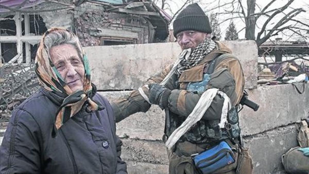 Un miliciano prorruso se quita una cinta identificativa junto a una mujer mayor, en Debáltsevo, este jueves.