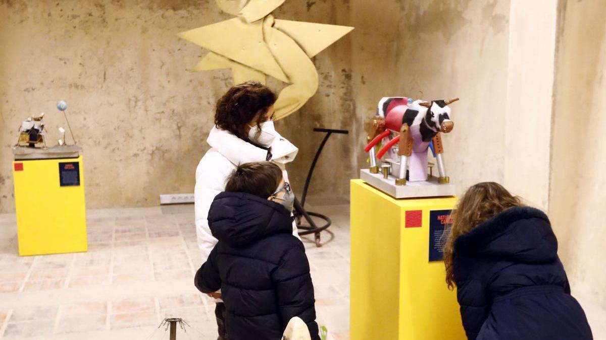 Dos niños observan junto a su madre una de las piezas de la exposición.