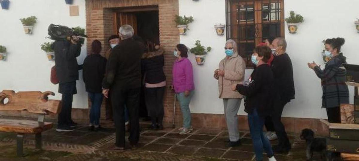 Vecinos cantando villancicos acompañan al reparto de los jamones.