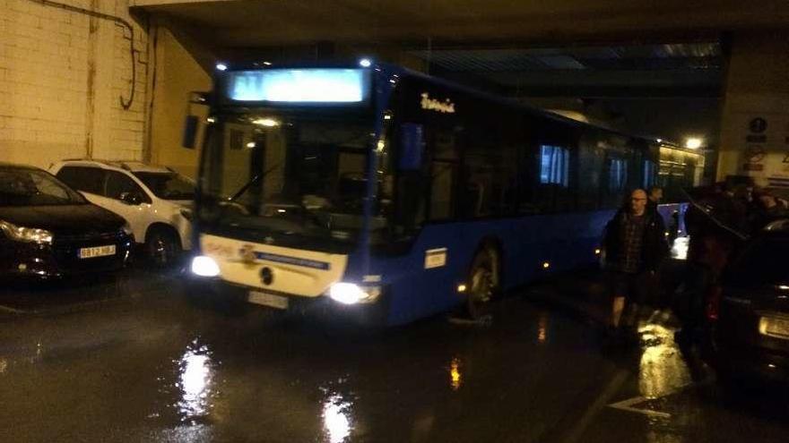 Un autobús sale de la cochera de la CTEA a primera hora de la mañana de ayer para realizar servicios mínimos; a la derecha, miembros del comité de empresa y sindicalistas llegados desde Oviedo en apoyo de los huelguistas.