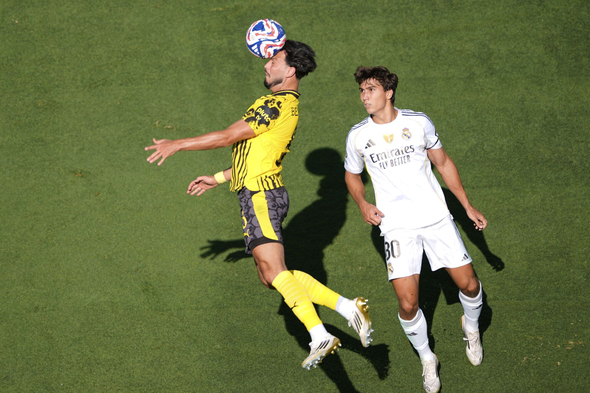 Borussia Dortmund's Ramy Bensebaini, left, heads the ball past Real Madrid's Gonzalo Garcia during the Club World Cup quarterfinal soccer match between Real Madrid and Borussia Dortmund in East Rutherford, N.J., Saturday, July 5, 2025. (AP Photo/Pamela Smith)