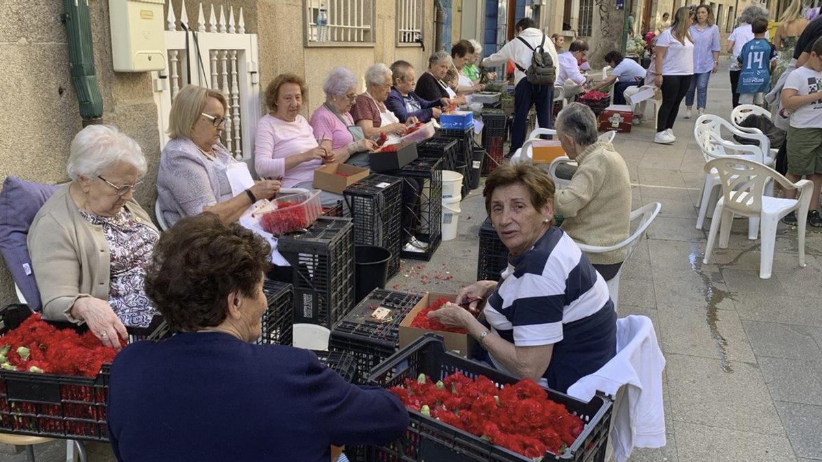 Las alfombristas trabajando en la calle Isidoro Queimaliños, ayer, en el centro de Redondela.