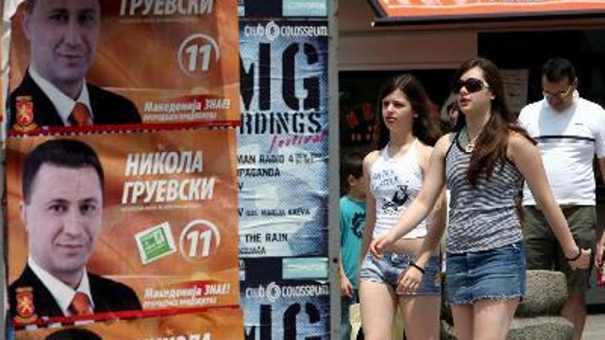 Dos chicas pasan junto a un carteles electorales de la formación gubernamental y conservadora Organización Revolucionaria Macedonia del Interior (VMRO-DPMNE) con la foto del primer ministro Nikola Gruevski por las calles de la capital Skopje, Macedonia.