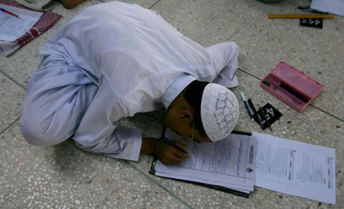 Un estudiant religiós s’examina, sense taula ni cadira, al seminari islàmic Jamia Binoria a Karachi, Pakistan.