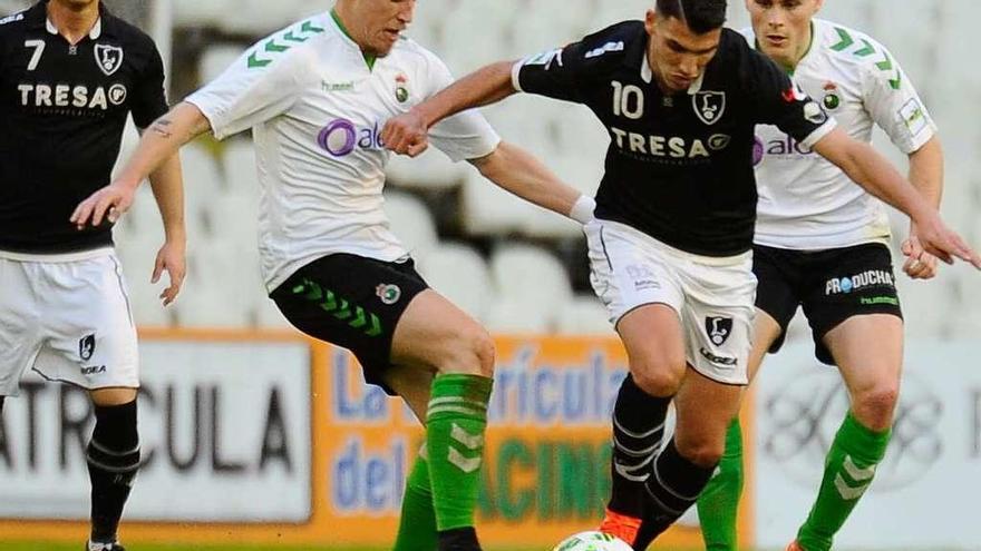 David Grande intenta superar a dos contrarios en el partido ante el Racing de Santander.